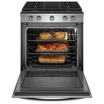 A variety of dishes cooking on the gas burners of the stove, with sizzling pots and pans on the cooktop.